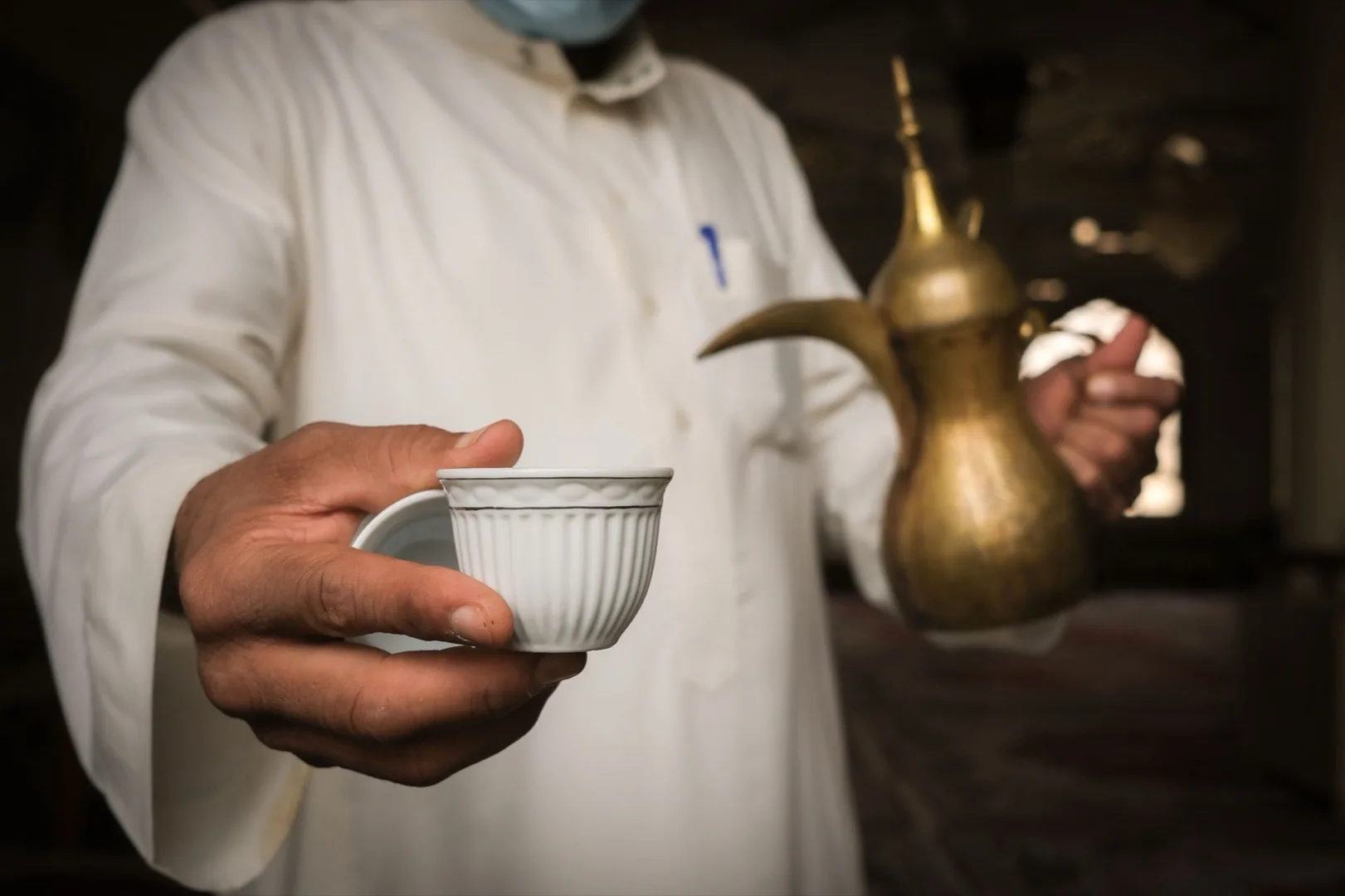Emirati man in traditional attire pouring Arabic Gahwa coffee