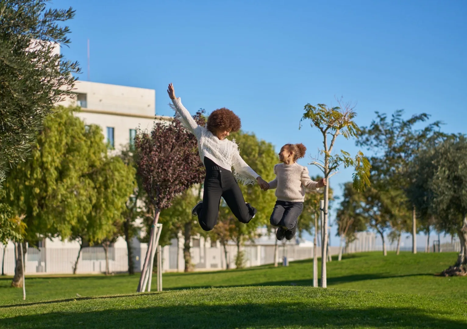 Two children jumping joyfully in a residential community park