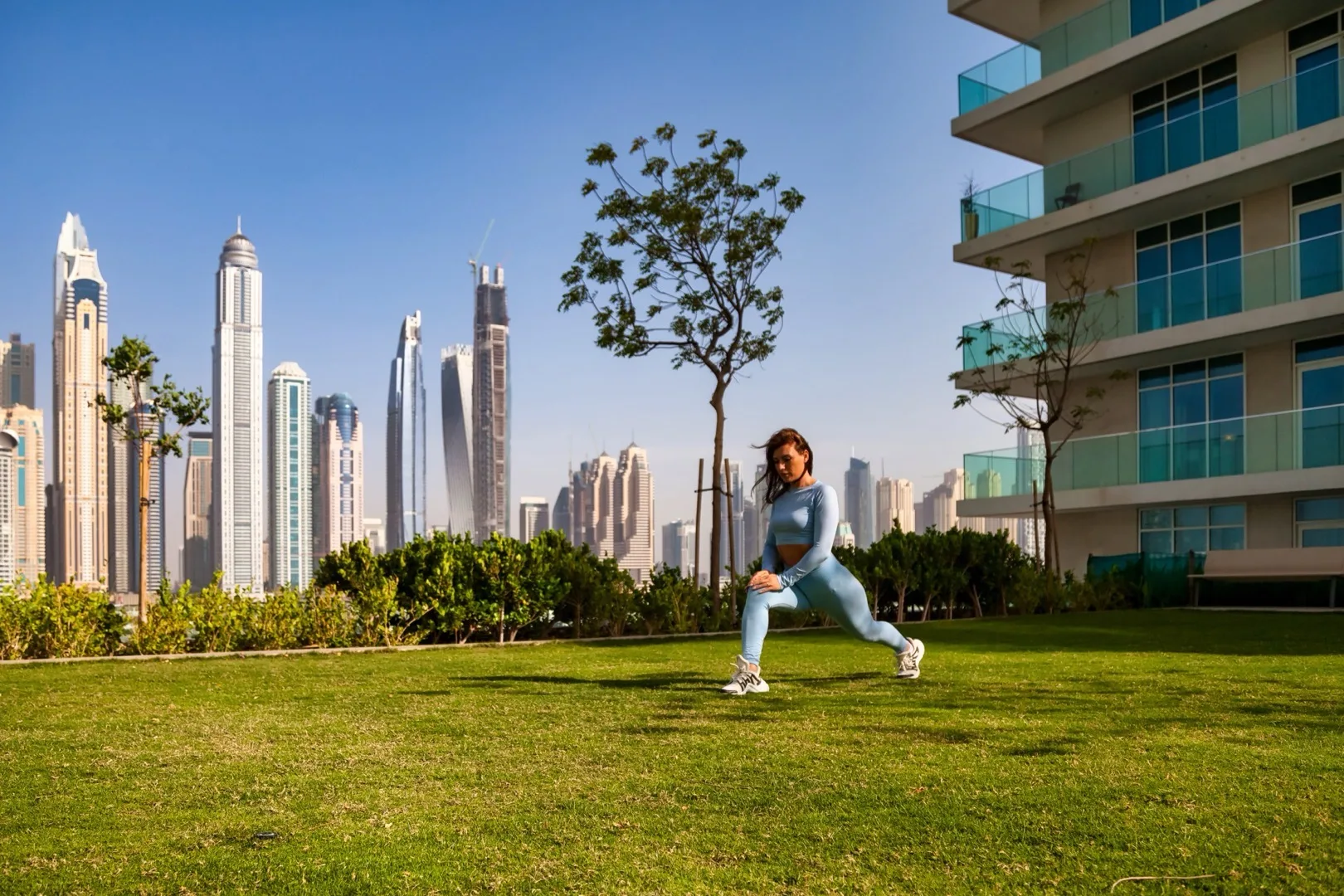 Woman exercising in community park with Dubai skyline