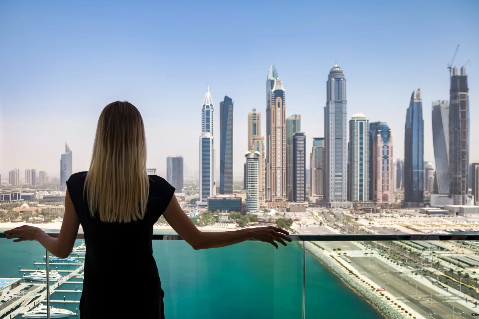 Woman enjoying Dubai Marina skyline view from apartment balcony