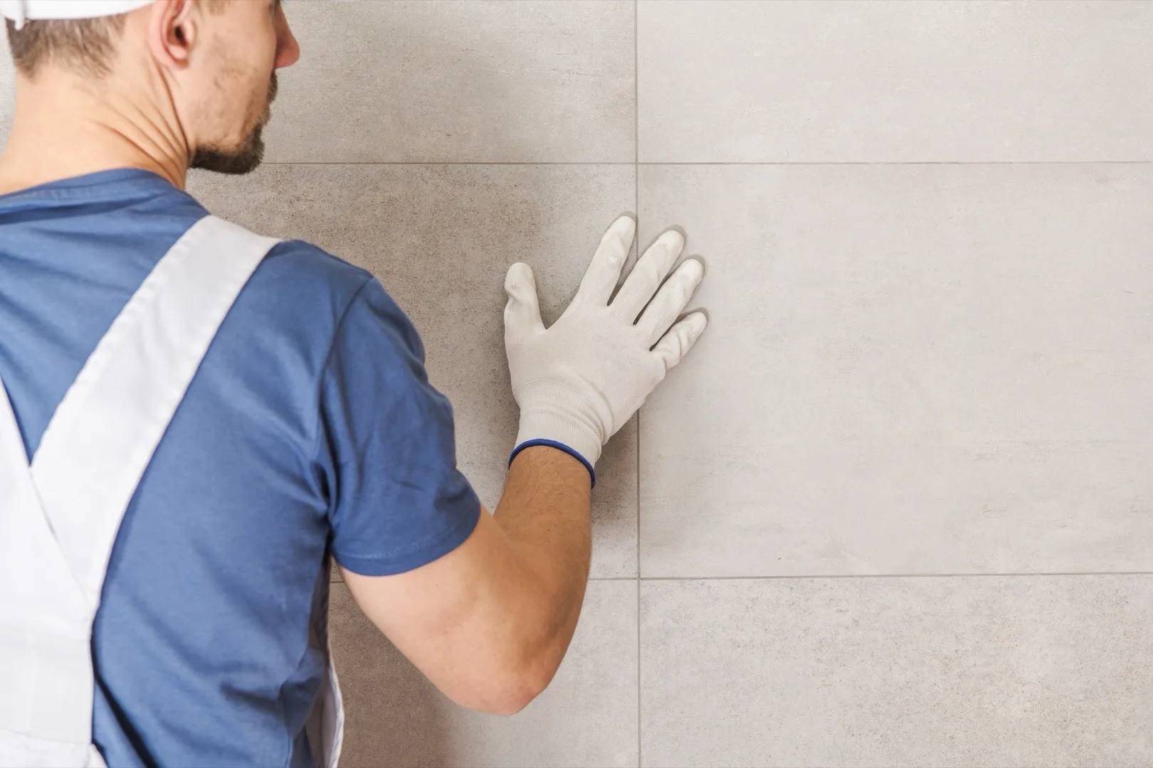 Worker inspecting ceramic wall tile alignment during construction