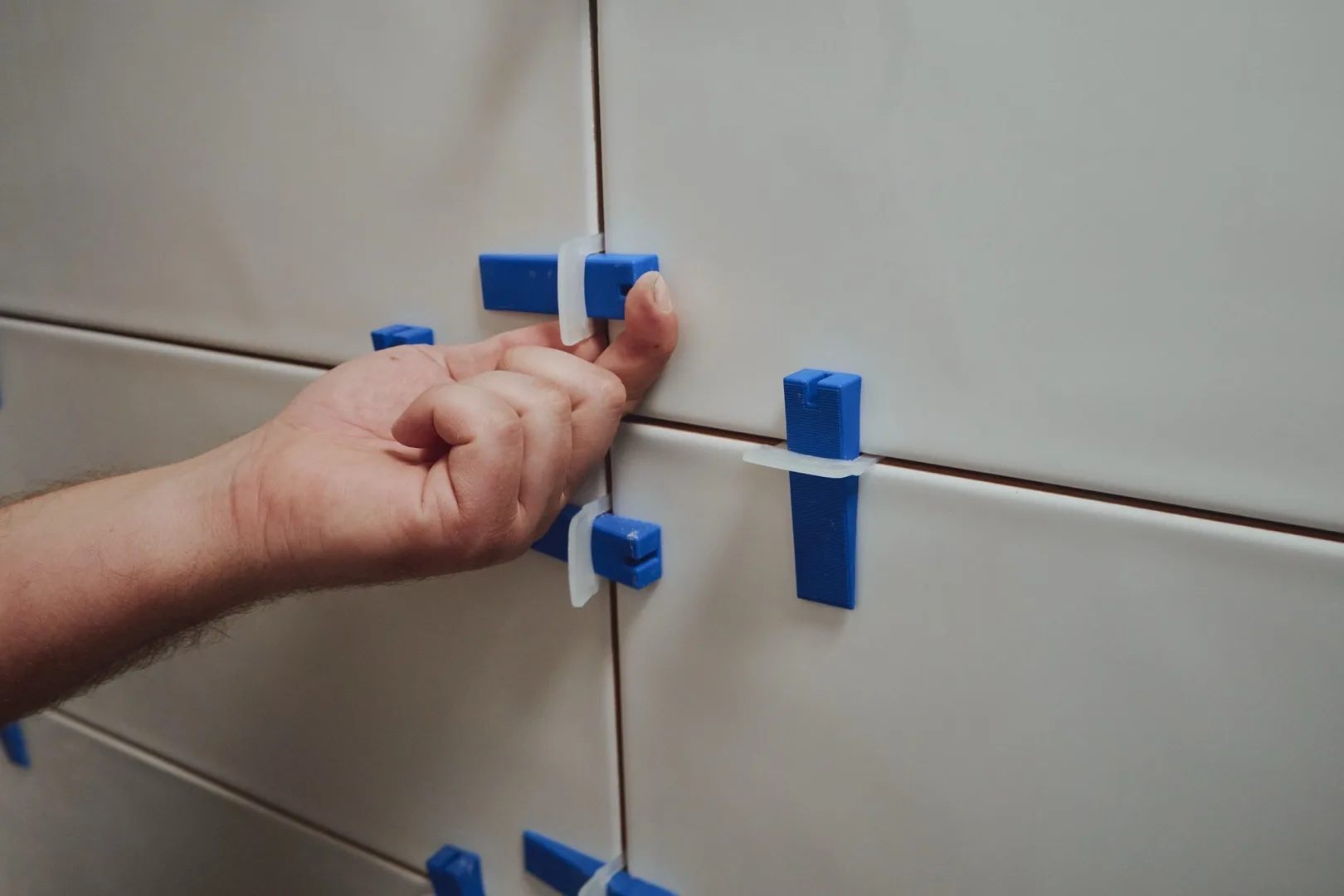Tiler using a leveling system to align ceramic wall tiles
